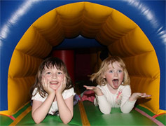 An image of two children playing in an inflatable